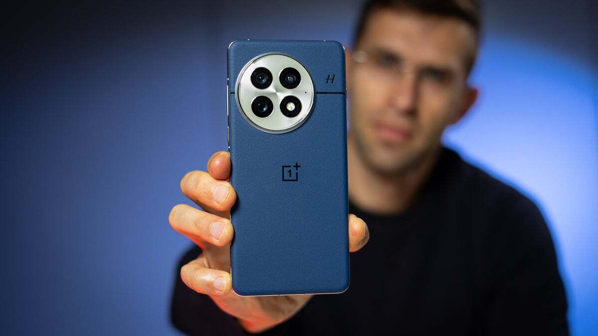 شخصی که OnePlus 13 را به رنگ آبی نشان می دهد ، پشت تلفن را نشان می دهد.