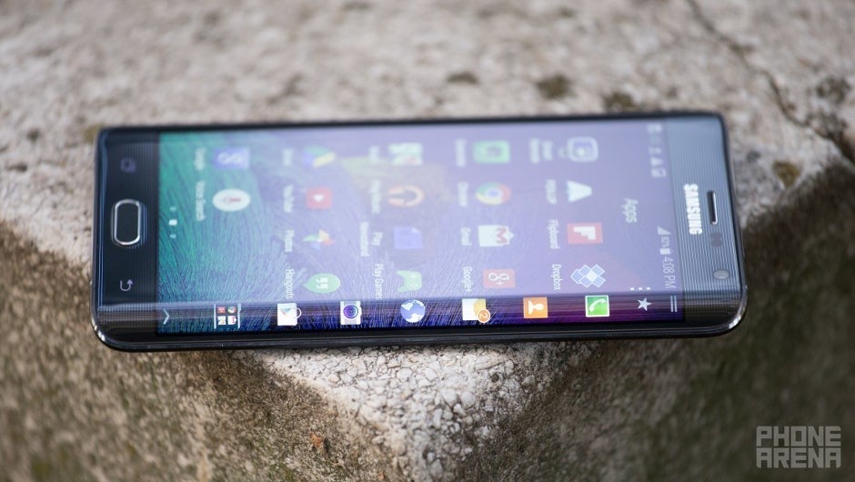 Samsung Galaxy Note Edge که در یک شکل صخره ای در جایی در خارج از منزل قرار دارد. در یک زاویه ، از طرف منحنی صفحه نمایش مشاهده می شود. صفحه نمایش روشن است ، نشان دادن صفحه اصلی و برنامه راه اندازی نوار.